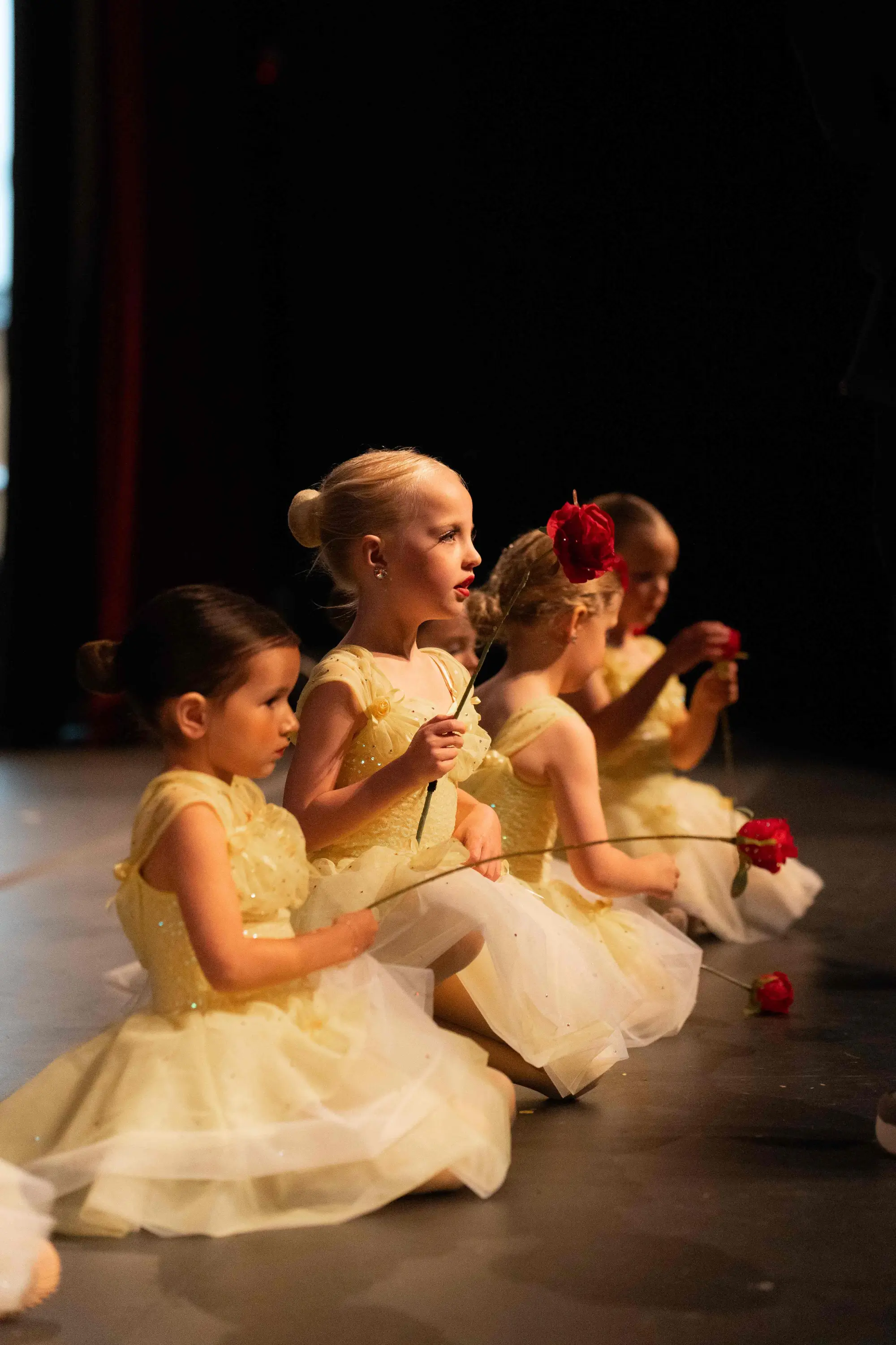 4 young female dancers  in golden dresses with roses